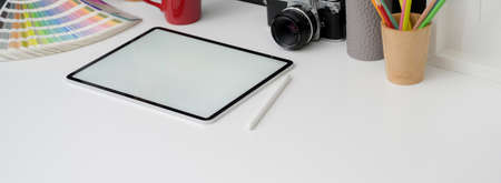 Cropped shot of photographer worktable with blank screen tablet, camera and supplies on white desk の写真素材