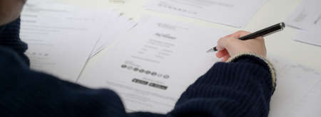 Close up view of businesswoman reading informations on financial document on white office desk の写真素材