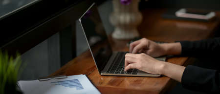 Cropped shot of businesswoman working with laptop and document paper on wooden counter bar in coffee...