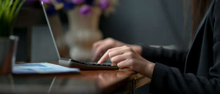 Side view of businesswoman working with calculator, laptop and document file on wooden counter bar...