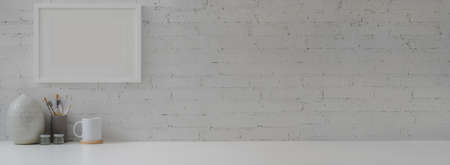 Close up view of contemporary home interior design with decorations, painting tools, cup and copy space on white table with brick wall  の写真素材