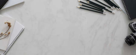 Top view of modern workspace with copy space, pencils, notebooks, camera and supplies on marble deskの写真素材