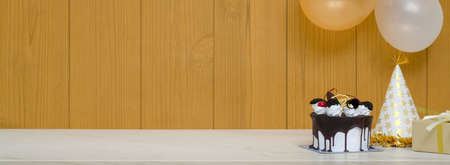 Close up view of marble table with birthday cake, copy space and balloon decorated on plank wallの写真素材