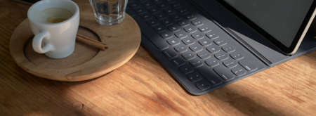 Cropped shot of portable workspace with digital tablet and coffee cup on wooden counter bar in cafeの写真素材