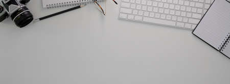 Top view of minimal worktable with computer devices, glasses, stationery, camera and copy space on...