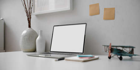 Cropped shot of minimal workspace with mock-up laptop, stationery, notepad and decorations 