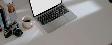 Top view of comfortable workspace with mock-up laptop, coffee cup, camera, stationery and copy space...