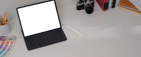 Cropped shot of designer office desk with mock-up tablet, camera, designer supplies, books and copy...