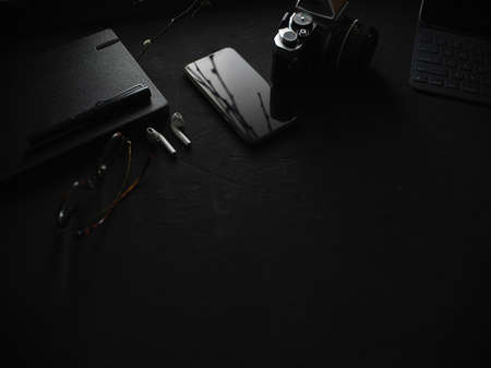 Cropped shot of dark modern concept workspace with camera, stationery, glasses, digital devices and copy space の写真素材