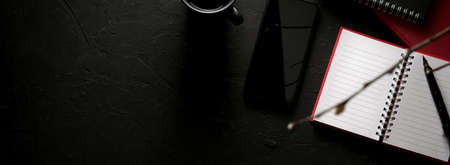 Top view of stylish workspace with open blank notebook, smartphone, coffee cup and copy space on black tableの写真素材