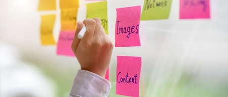 Close up view of female content creator noting an idea on  note on glass wallの写真素材