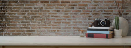 Close up view of contemporary home interior design with camera, books, decorations and copy space on marble desk with brick wallの写真素材