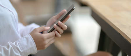 Side view of female university student using smartphone while sitting in cafeteria