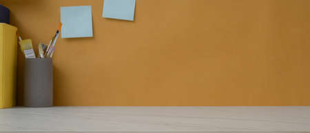Close up view of copy space on marble worktable with books, painting tools and notepad on yellow...