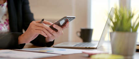 Side view of businesspeople looking information on smartphone while analysing business chart