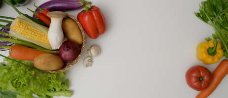 Top view of assorted fresh farm vegetables and copy space on white kitchen tableの写真素材