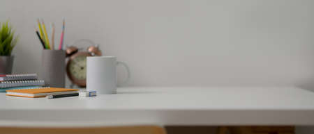 Close up view of home office desk with copy space, coffee mug, diary notebooks, stationery and decorationsの写真素材