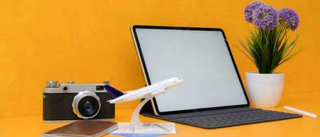 Travel preparation concept with mock-up tablet, camera, passport and decorations on yellow...