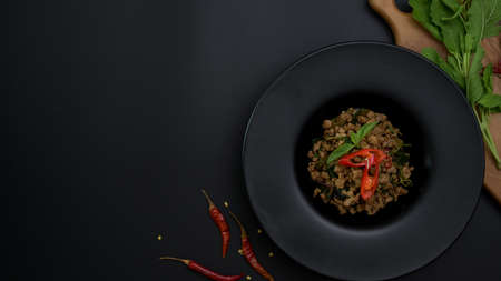 Top view of Thai traditional food, Stir fried minced pork with basil (Pad ka prao)  on black dinning table with ingredients and copy spaceの写真素材