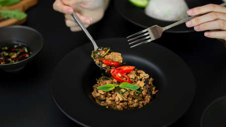 Cropped shot of female eating Thai traditional food, Stir fried minced pork with basil (Pad ka prao) in Thai restaurantの写真素材