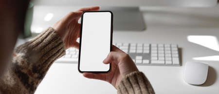 Close up view of female employee looking information on mock-up smartphone while working at office...