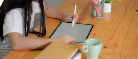 Close up view a girl relaxing with mock-up digital tablet on wooden worktable after finish her...