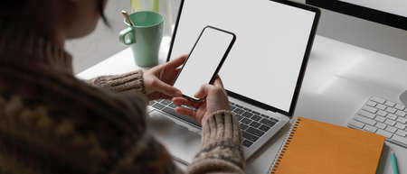 Cropped shot of female university student looking information on mock-up smartphone while doing...