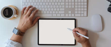 Overhead shot of businessman using blank screen tablet and working with computer device on white...