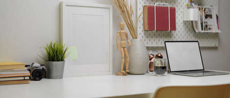 Cropped shot of modern office desk with copy space, mock-up laptop, office supplies and decorations 