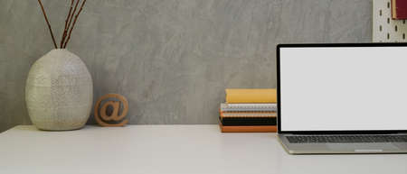 Close up view of designer worktable with copy space, mock-up laptop, stationery, painting tools,...
