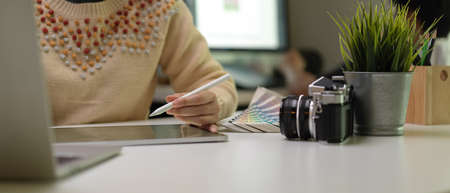 Cropped shot of female designer drawing on digital tablet while working with laptop and designer...