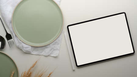 Top view of dinning table with mock-up tablet, turquoise ceramic plates, napkin and golden wheat decorated on tableの写真素材