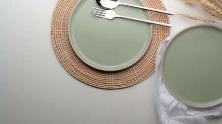Top view of dinning table with mock-up turquoise ceramic plates and silverware on placemat and napkin on white tableの写真素材