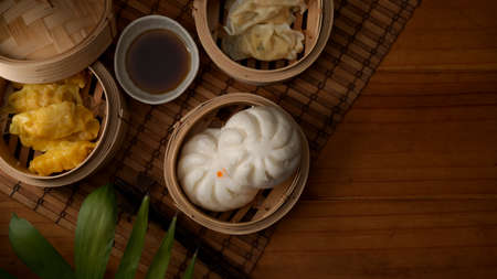 Top view of steamed dumplings serving on bamboo seamer with hot tea on wooden table with copy spaceの写真素材