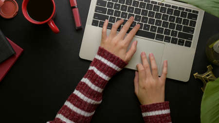 Overhead shot of female typing on laptop keyboard on stylish office desk with office supplies,...