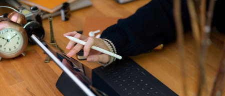 Cropped shot of female worker working with digital tablet on wooden office desk with supplies and decorationsの写真素材