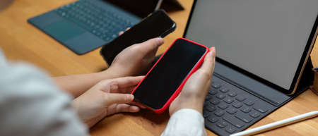 Side view of female college students sharing informations on smartphone while working with tablet on...