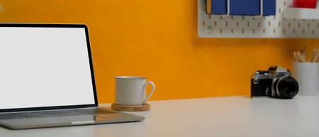 Cropped shot of stylish workspace with mock-up laptop, coffee cup, copy space, camera and supplies