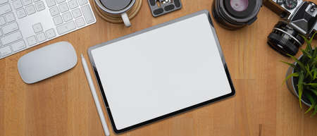 Overhead shot of male taking note on blank notebook on white office desk with computer device,...