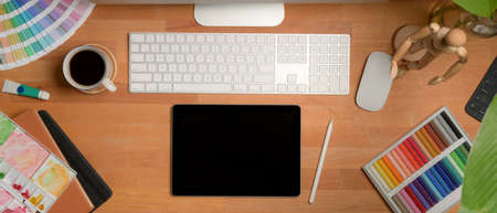 Overhead shot of male taking note on blank notebook on white office desk with computer device, camera and coffee cupの写真素材