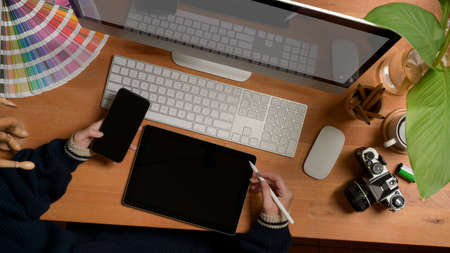 Overhead shot of male taking note on blank notebook on white office desk with computer device, camera and coffee cupの写真素材