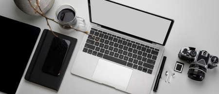 Top view of modern worktable with mock-up tablet, laptop, copy space, camera and stationery on...