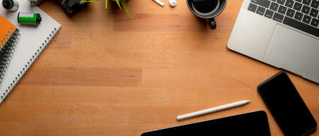 Top view of modern worktable with mock-up tablet, laptop, copy space, camera and stationery on...