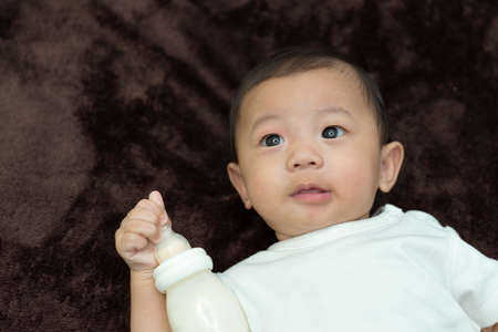 Top view of happy baby boy lying on  brown sheet
