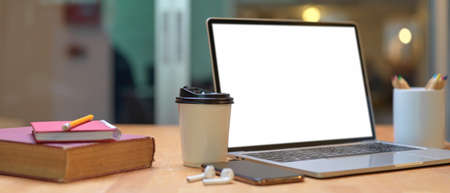 Cropped shot of study table with books, mock up laptop, smartphone, earphone, stationery and paper...