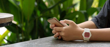 Close up view of a girl using smartphone white relaxed sitting on coffee table in garden