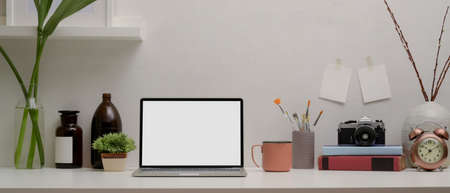 Close up view of blank screen laptop on white desk with supplies and decorations in home office room