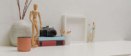 Cropped shot of modern workspace with copy space, mug, painting tools, camera, books and decorationsの写真素材