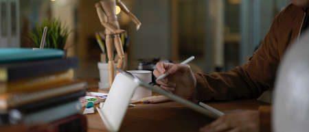 Side view of female college student doing assignment with digital tablet, books and supplies on...