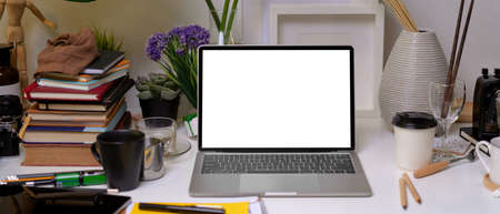 Close up view of home office with mock up laptop, stack of books, supplies, stationery and...